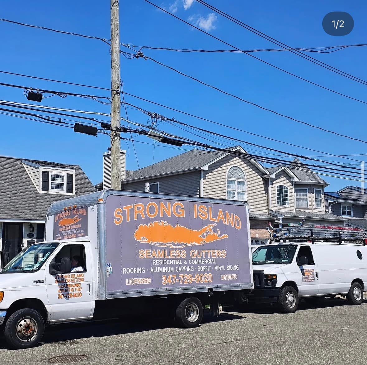 The Strong Island Seamless Gutters box truck and work van parked on a residential street, the truck lettered with the Long Island silhouette and phone number.